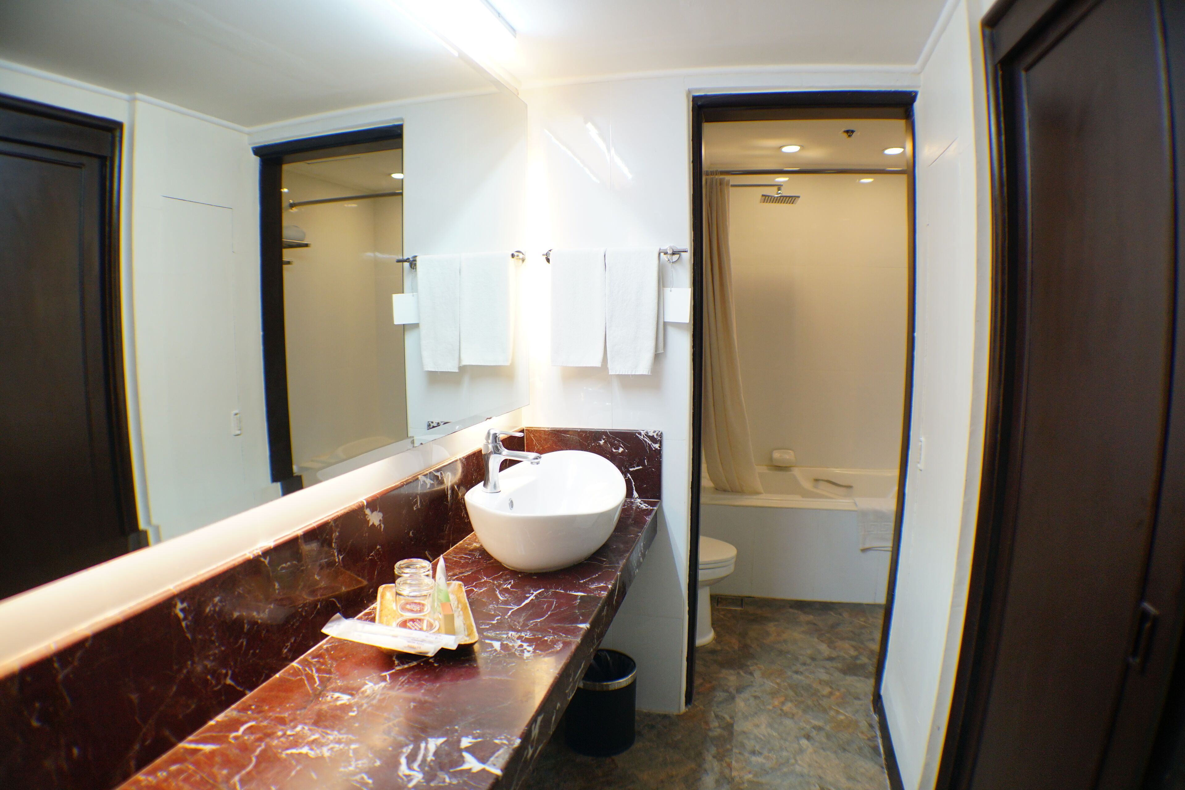 A bathroom with a marble countertop, a sink, and a shower.