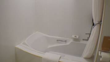 A bathroom with a bathtub, toilet, and shower curtain.