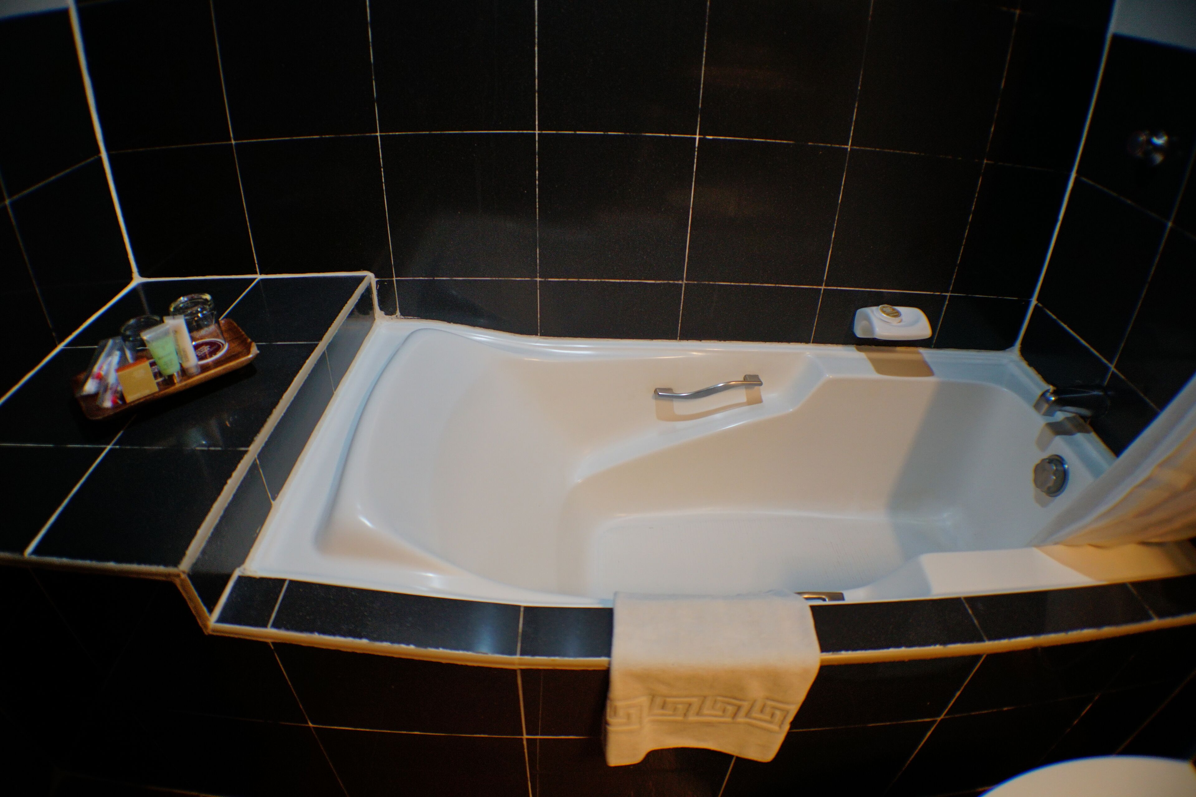 Un baño moderno con una bañera independiente, un pequeño recipiente con artículos de aseo y una toalla colgada a un lado.