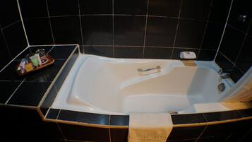A modern bathroom with a freestanding bathtub, a small tray with toiletries, and a towel hanging on the side.