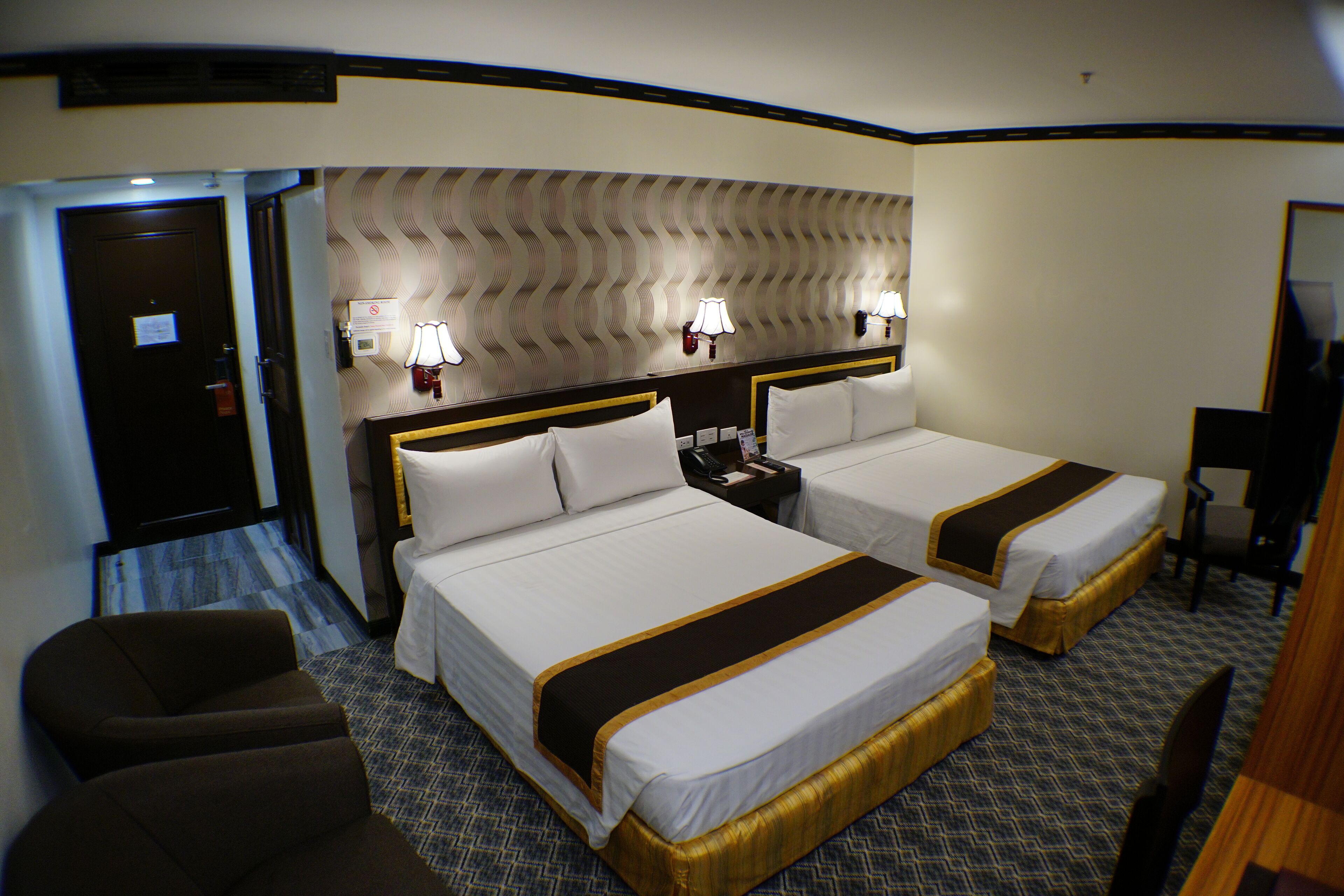 Een hotelkamer met twee bedden, een bureau en een stoel.