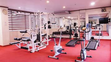 Ein Fitnessstudio mit verschiedenen Trainingsgeräten, darunter Laufbänder, Kraftgeräte und Kurzhanteln.