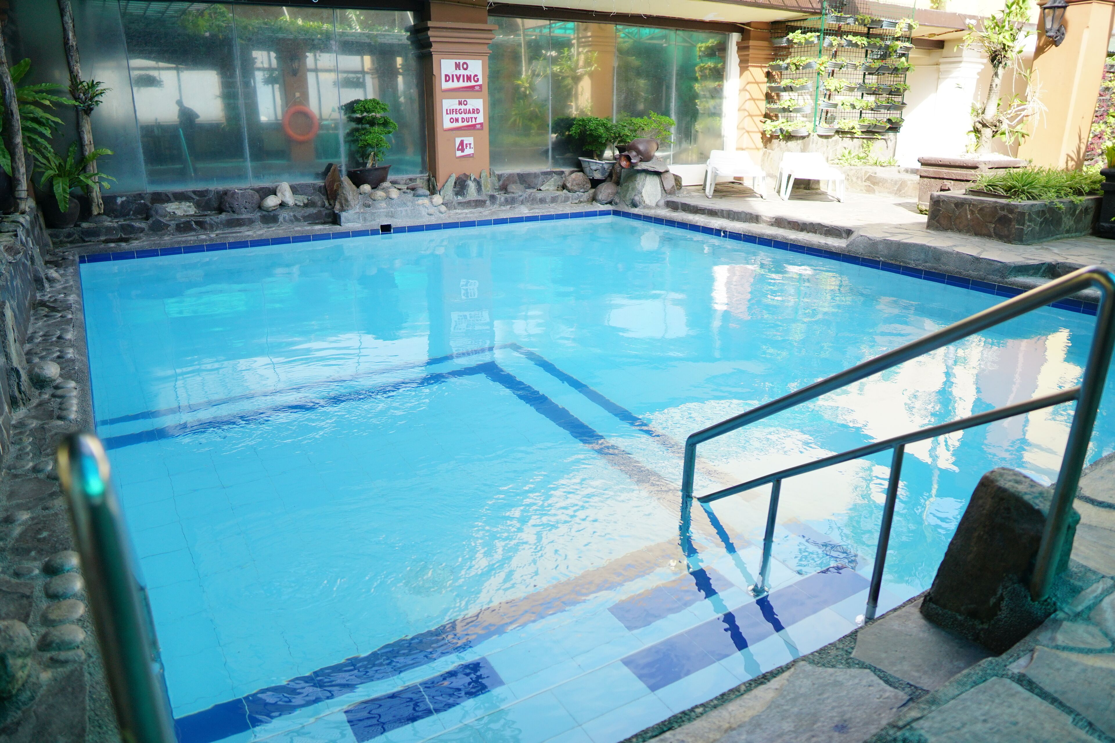 A swimming pool with a no diving sign, a lifeguard duty sign, and a 4 ft. depth marker.