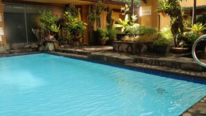 A swimming pool with a stone edge and surrounding potted plants. - Bayview Park Hotel Manila (Manila)