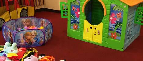 A play area with a green playhouse, a ball pit, and various toys.