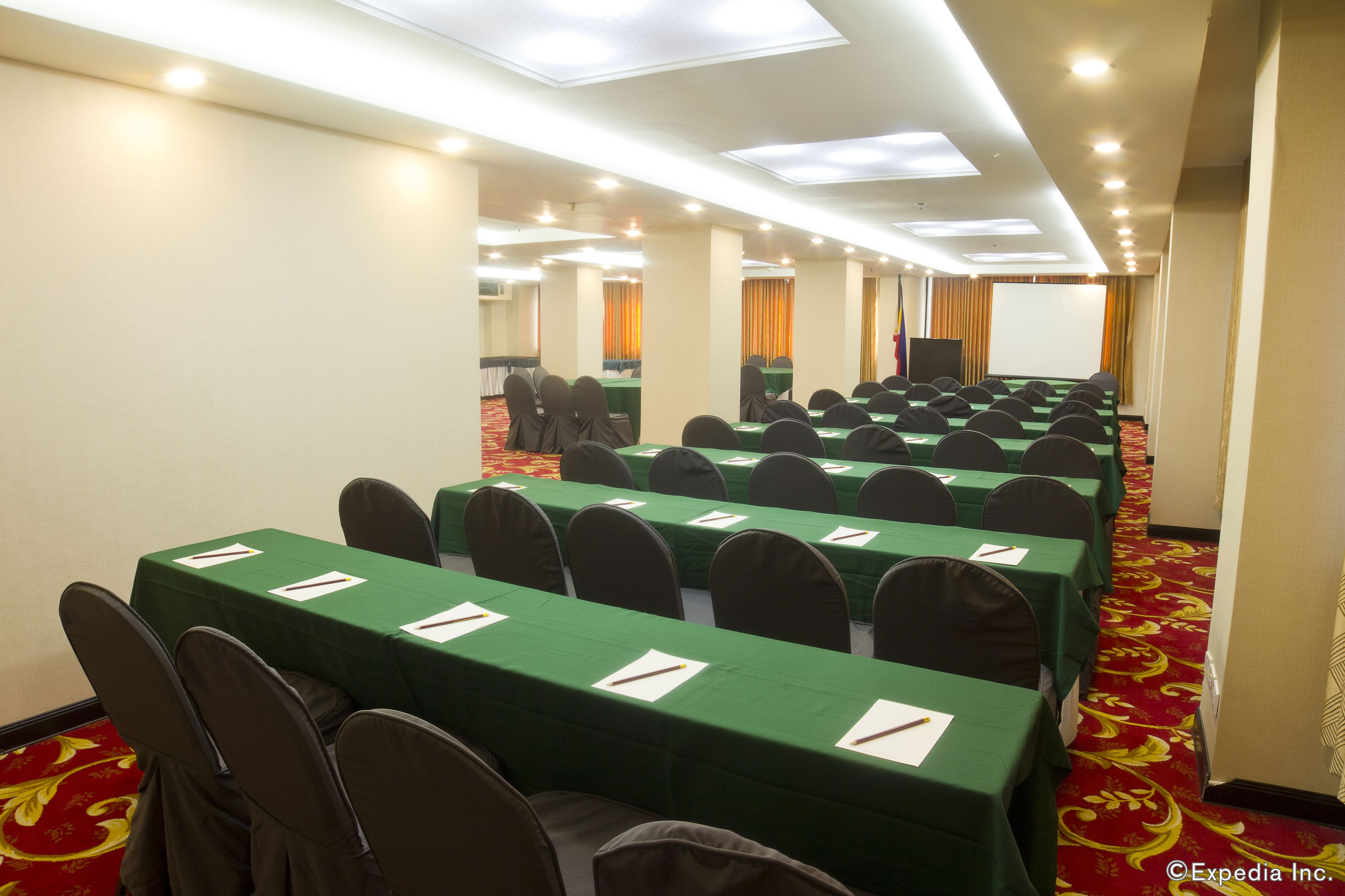 A conference room with rows of tables, chairs, and a projector screen.