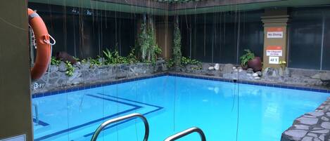Una piscina con techo de azulejos, un flotador salvavidas y un letrero que indica una profundidad de 1.2 metros.