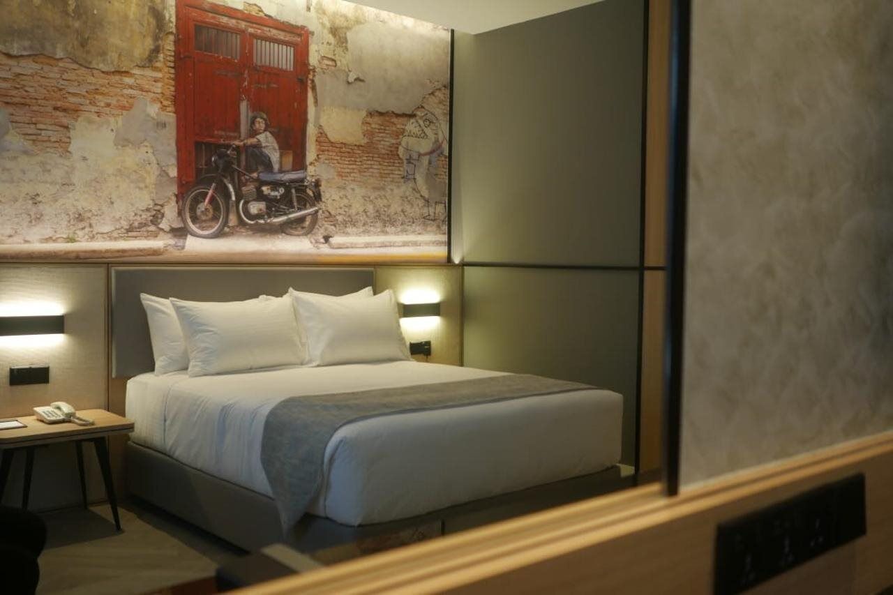 Een hotelkamer met een bed, nachtlampjes, een nachtkastje en een muurschildering.