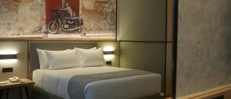 Een hotelkamer met een bed, nachtlampjes, een nachtkastje en een muurschildering.