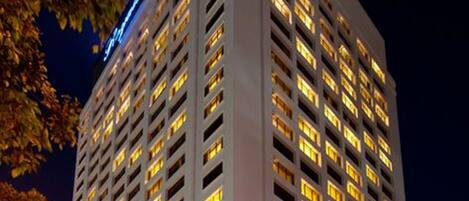 A tall hotel with multiple floors, illuminated windows, and a prominent sign at the top.