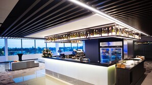 A modern bar area with a wine display, seating, and a view of the cityscape.