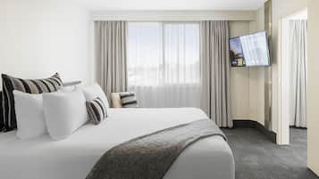 Une chambre d’hôtel avec un grand lit, un téléviseur à écran plat et une vue sur l’extérieur à travers des rideaux transparents.
