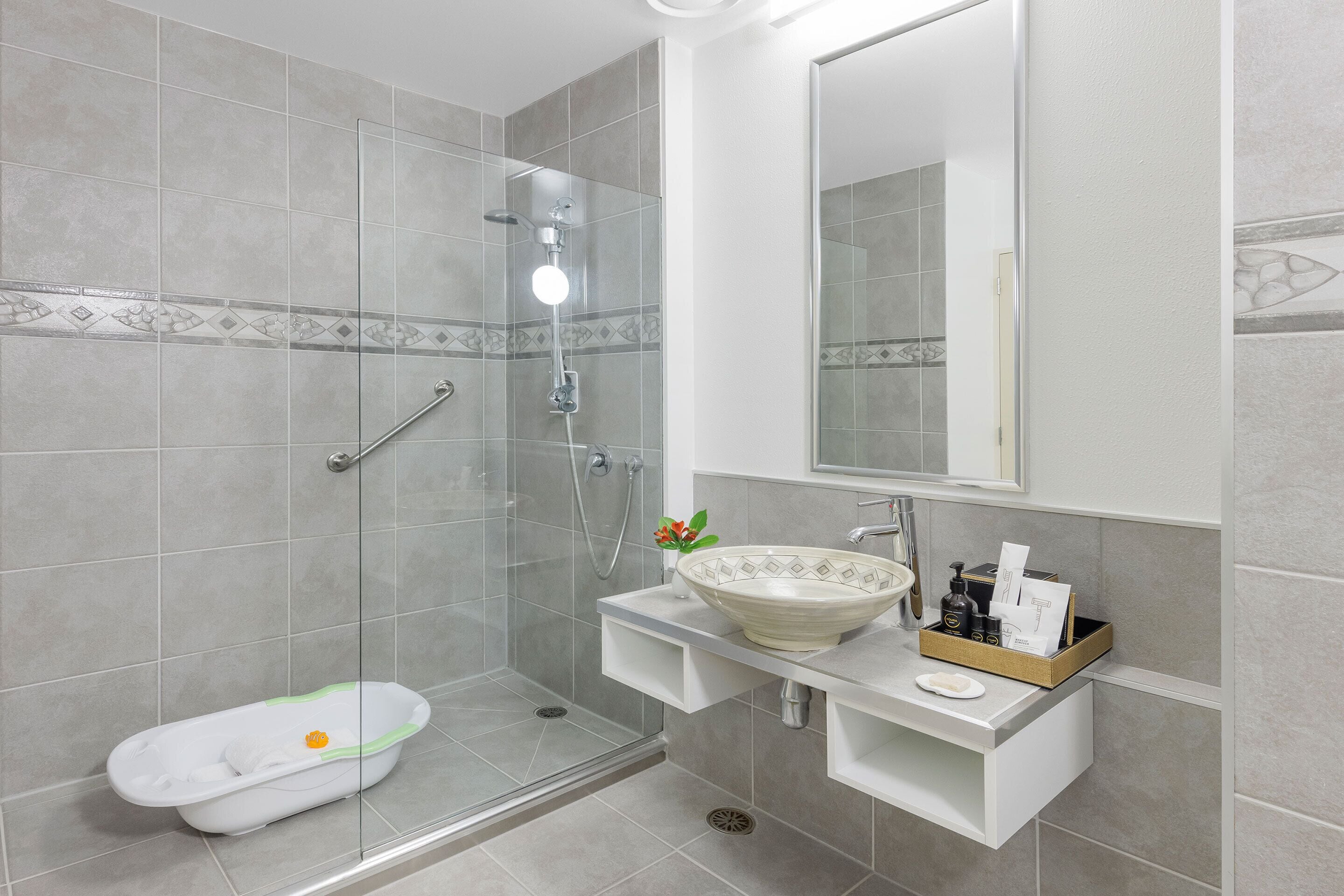 Un baño moderno con ducha acristalada, bañera blanca y tocador con lavabo.