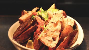 A bowl of roasted potatoes with slices of bread and a garnish of greens.