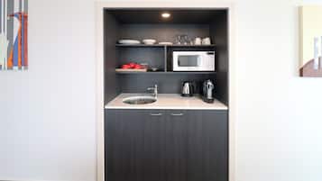 A compact kitchenette with a microwave, coffee maker, and a sink.