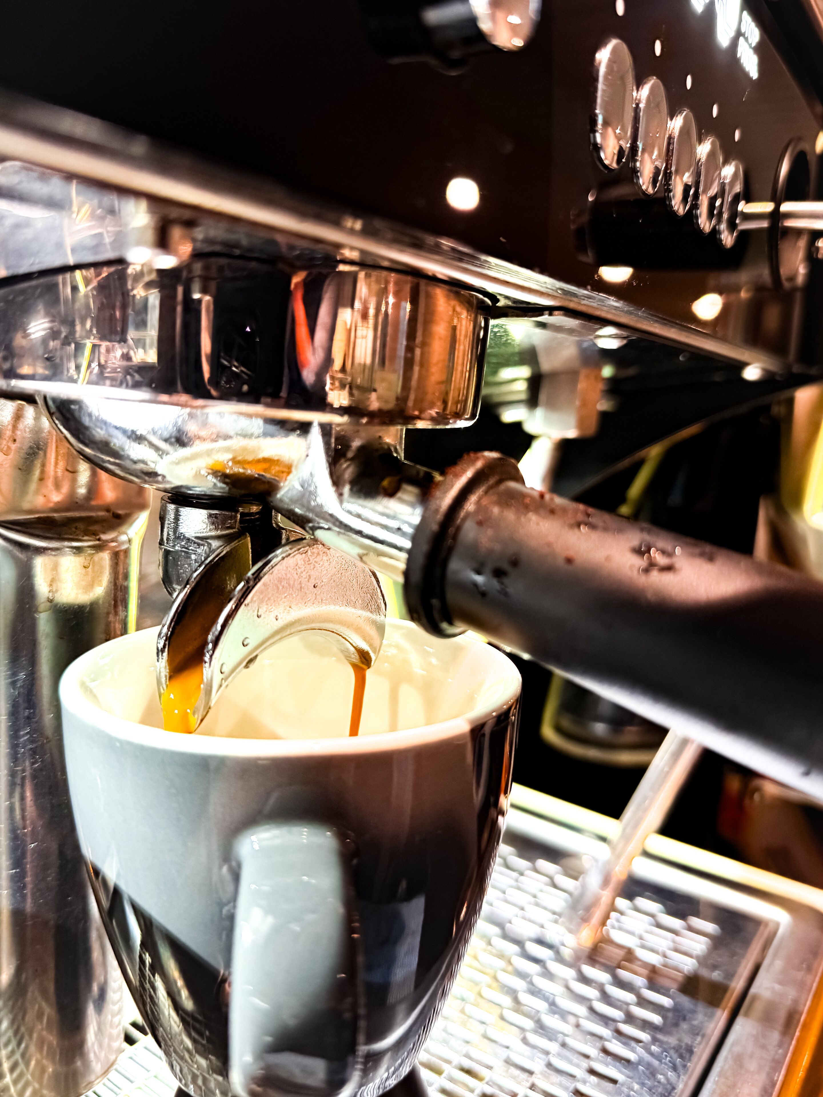 Un primo piano di una macchina del caffè che eroga un espresso in una tazza.