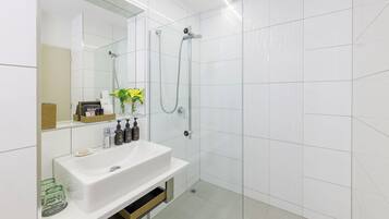 Un baño moderno con lavamanos, espejo y ducha blancos.