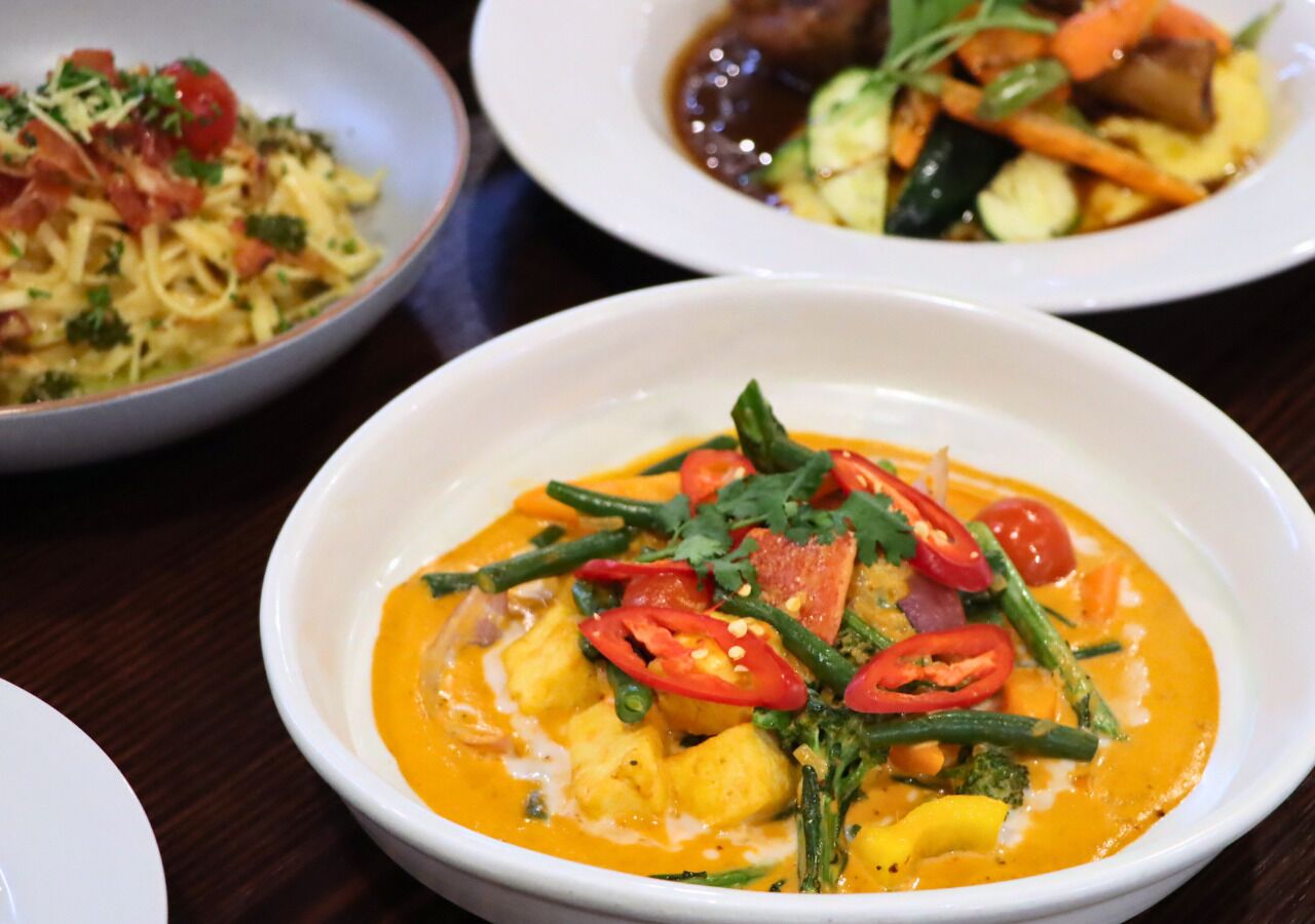 A table with three bowls of food, each containing different dishes.