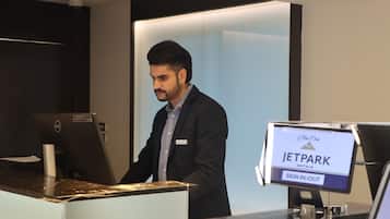 A man at a JetPark hotel reception desk with a sign-in/out monitor.