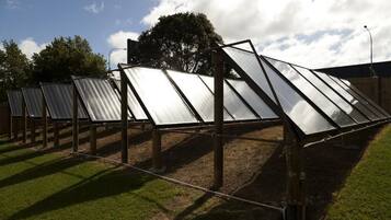A row of solar panels mounted on a wooden structure in an outdoor setting.