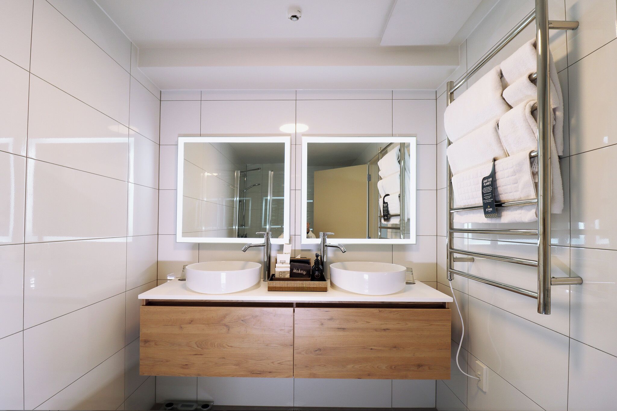 A modern bathroom with two sinks, a mirror, and a towel rack.