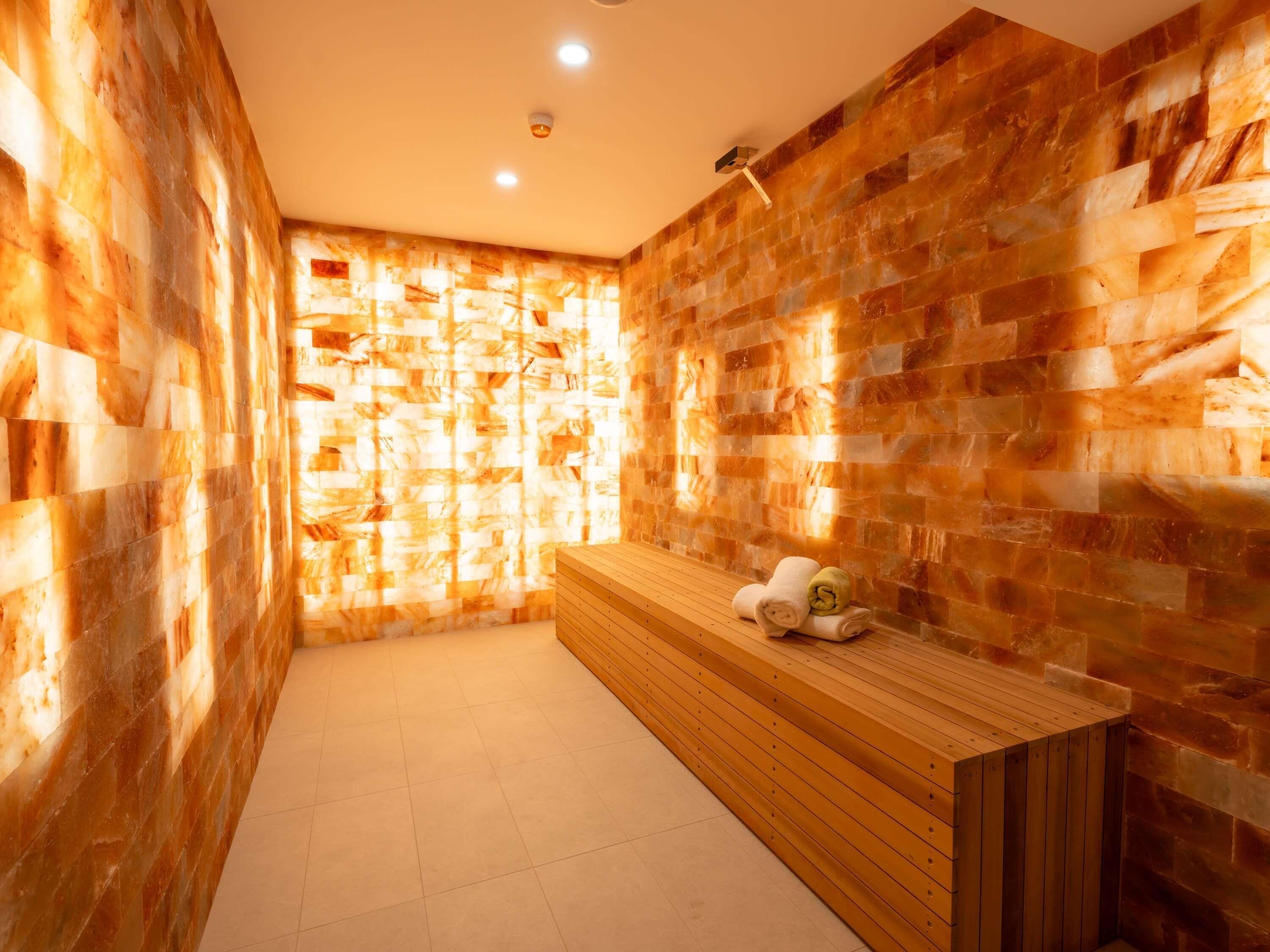 A spa room with a wooden bench, a towel, and a wall with a textured pattern.