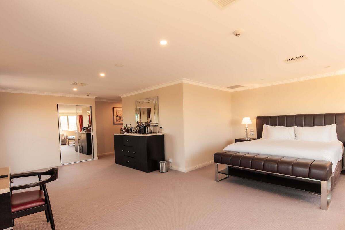 A hotel room with a bed, a desk, a dresser, and a mirror.