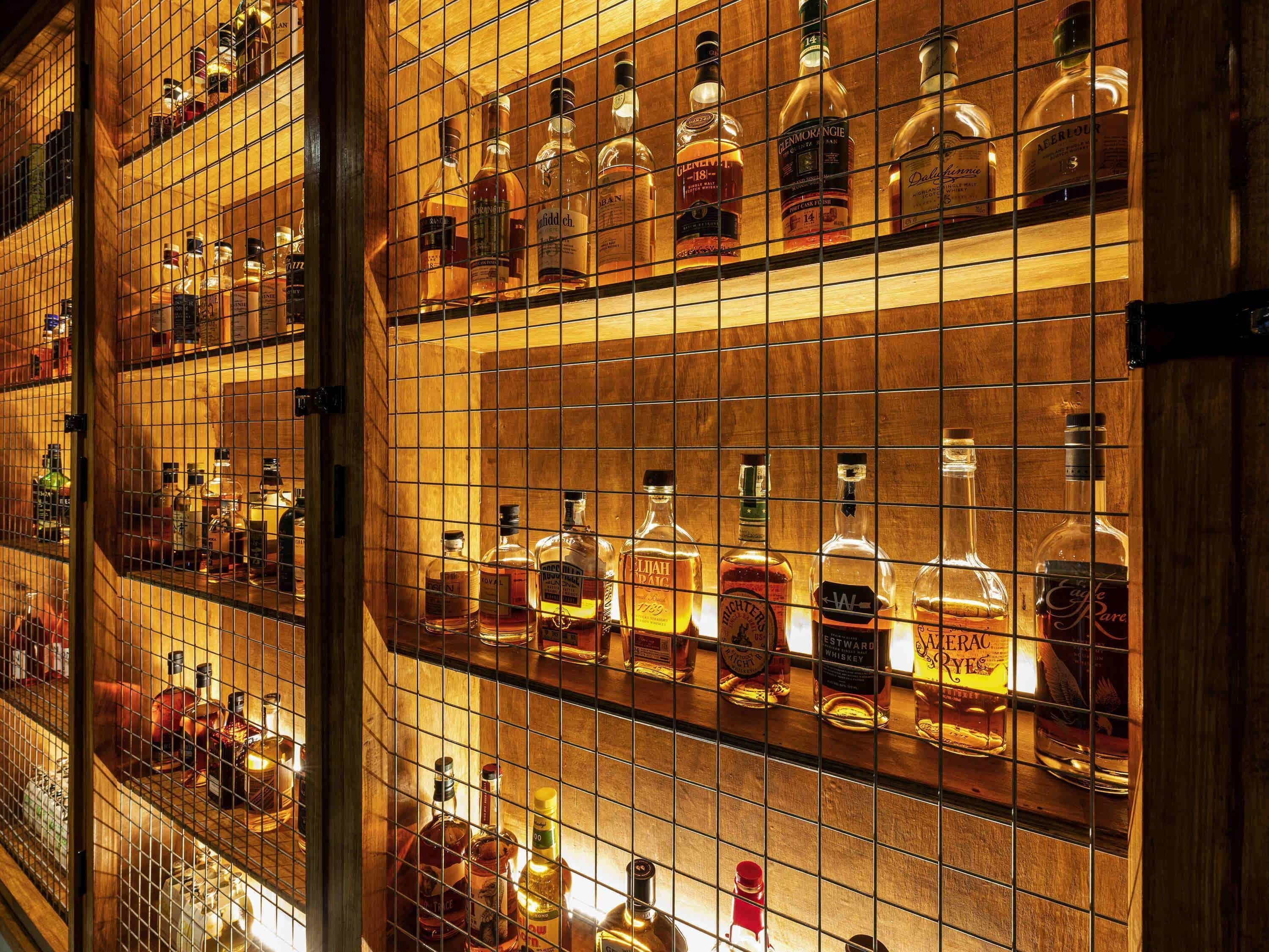 Zona de bar con estantes llenos de botellas de licores variados, incluyendo whiskey y otras bebidas espirituosas.