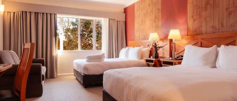 A hotel room with two beds, a desk, and a chair.