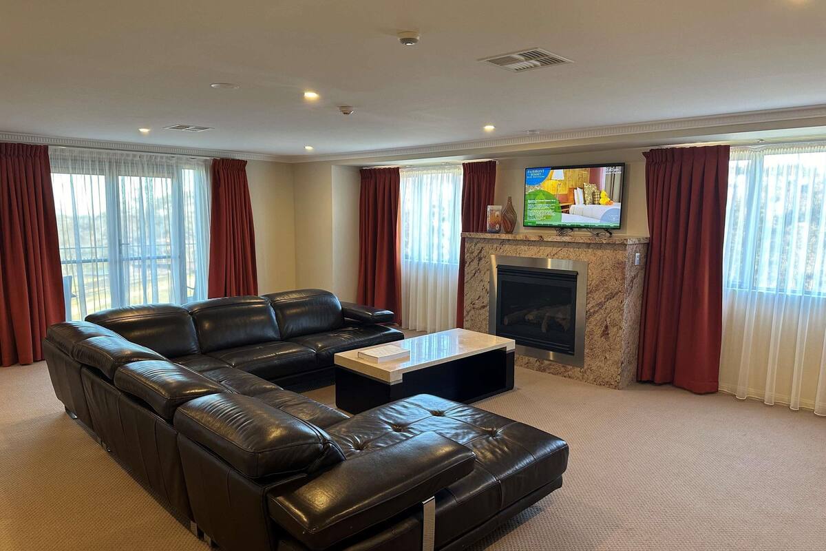 A living room with a sectional sofa, a flat-screen TV, and a fireplace.