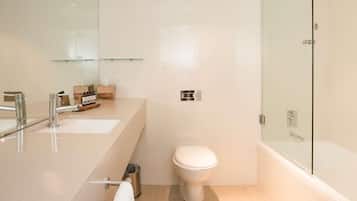 A modern bathroom with a glass shower enclosure, a white toilet, and a vanity with a mirror and two sinks.