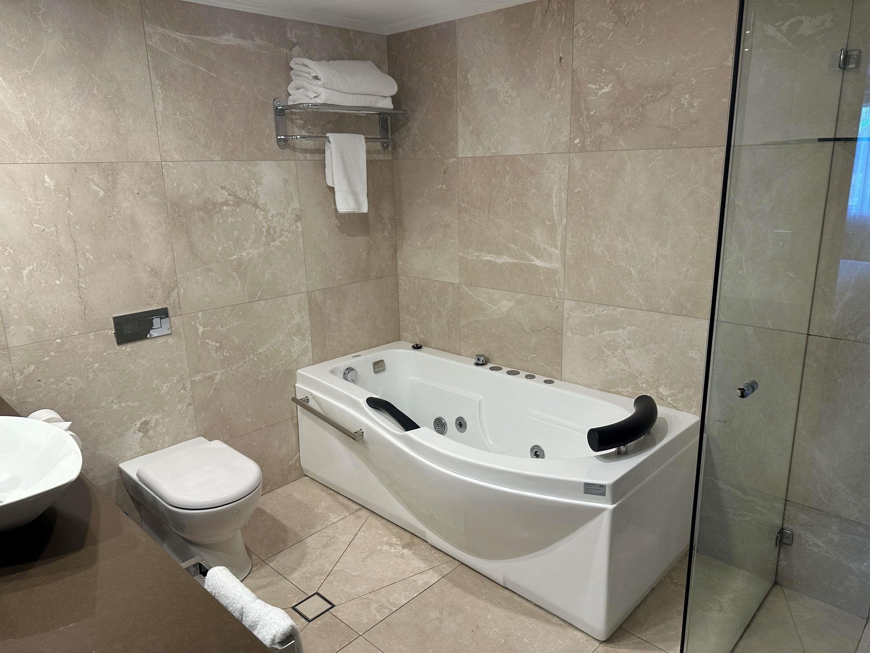 A modern bathroom with a large bathtub, a toilet, and a glass shower enclosure.