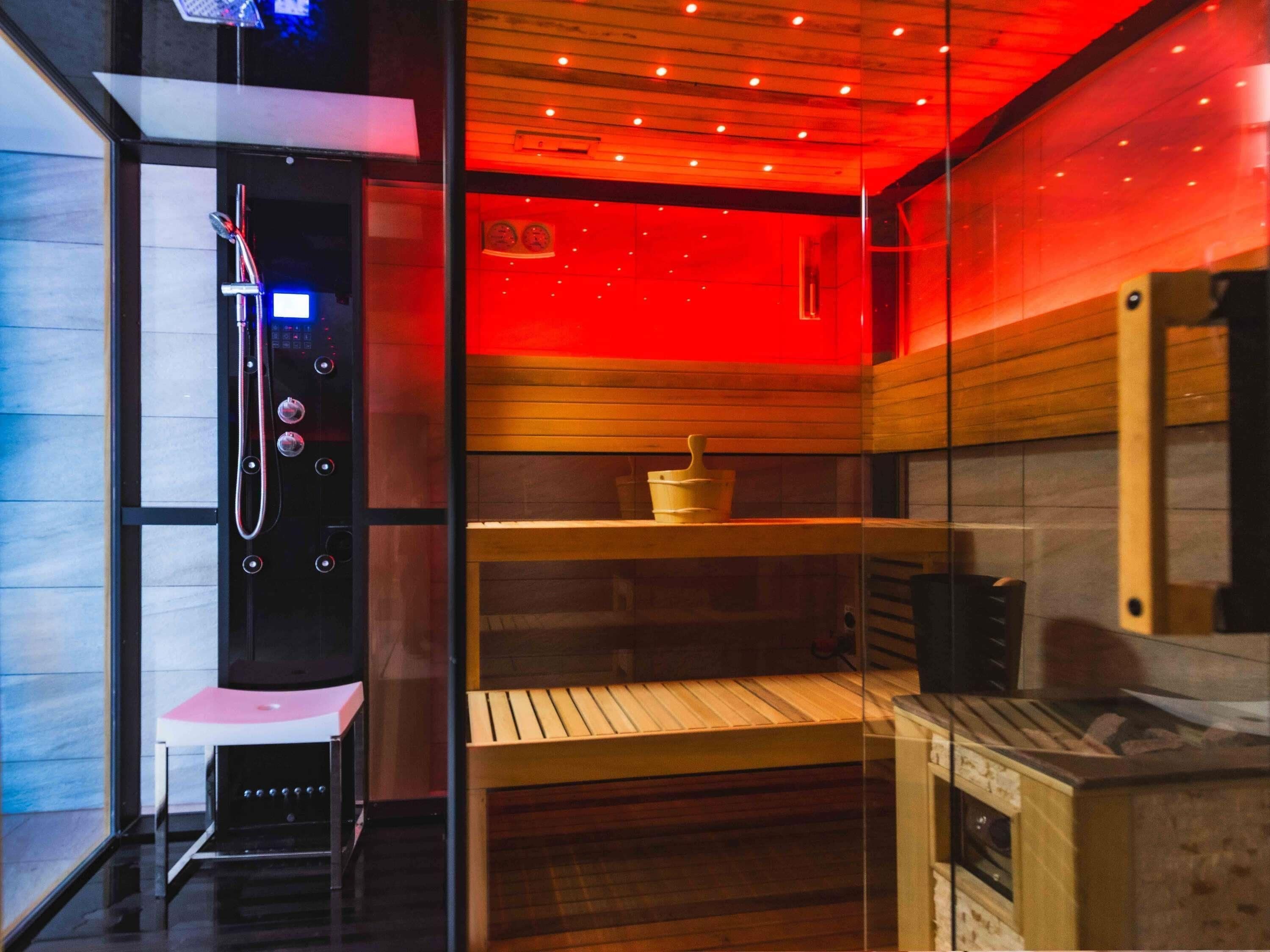 A sauna with wooden shelves, a bench, and a control panel.
