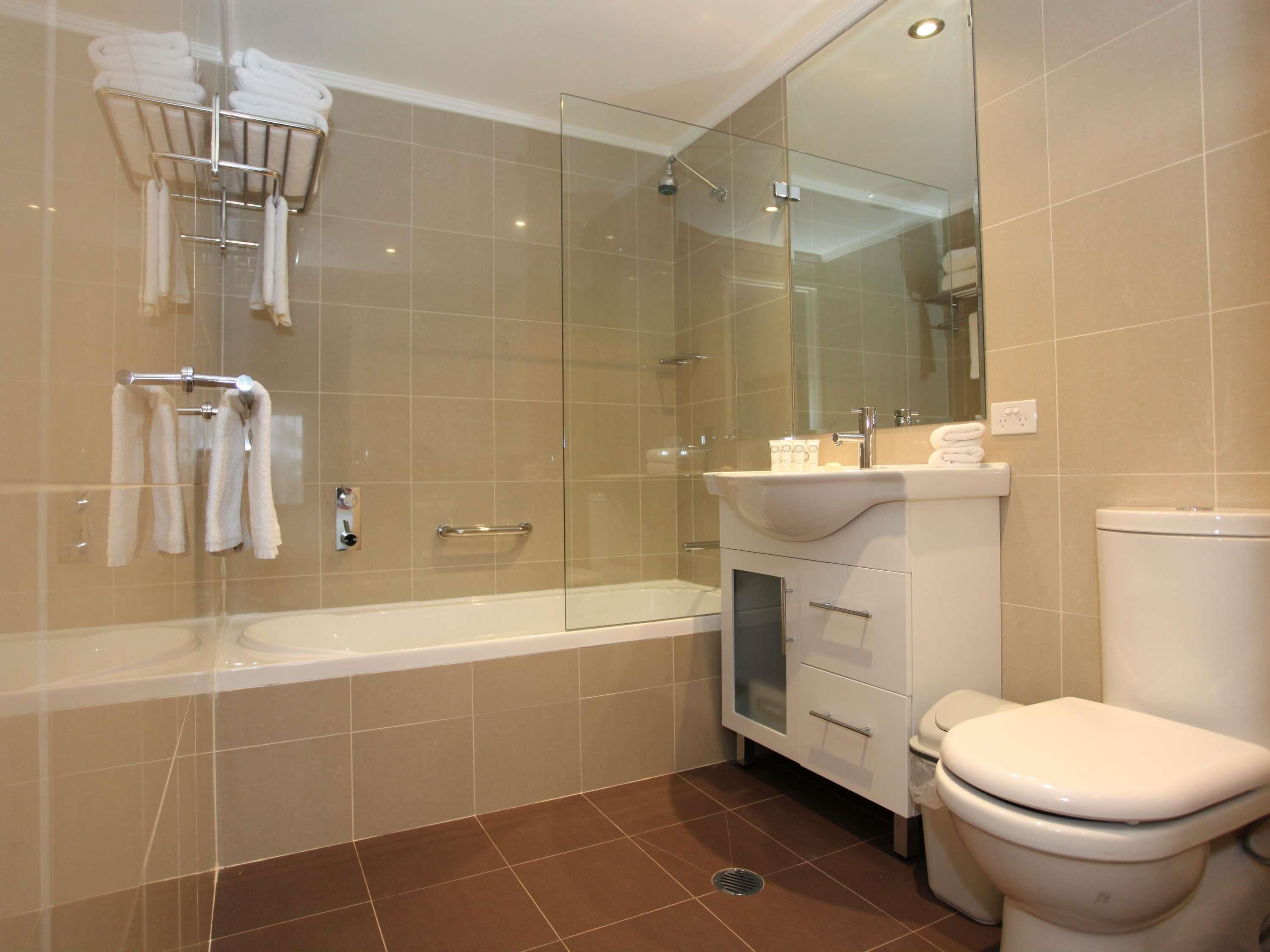 Une salle de bain moderne avec une douche à parois de verre, une baignoire blanche et des toilettes.