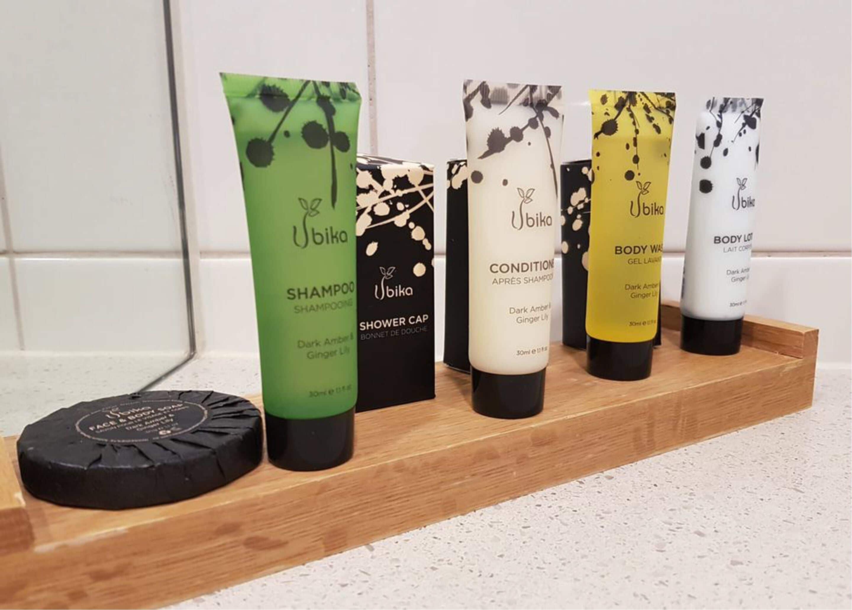 Una bandeja de madera con seis botellas de productos de cuidado corporal Ubika.