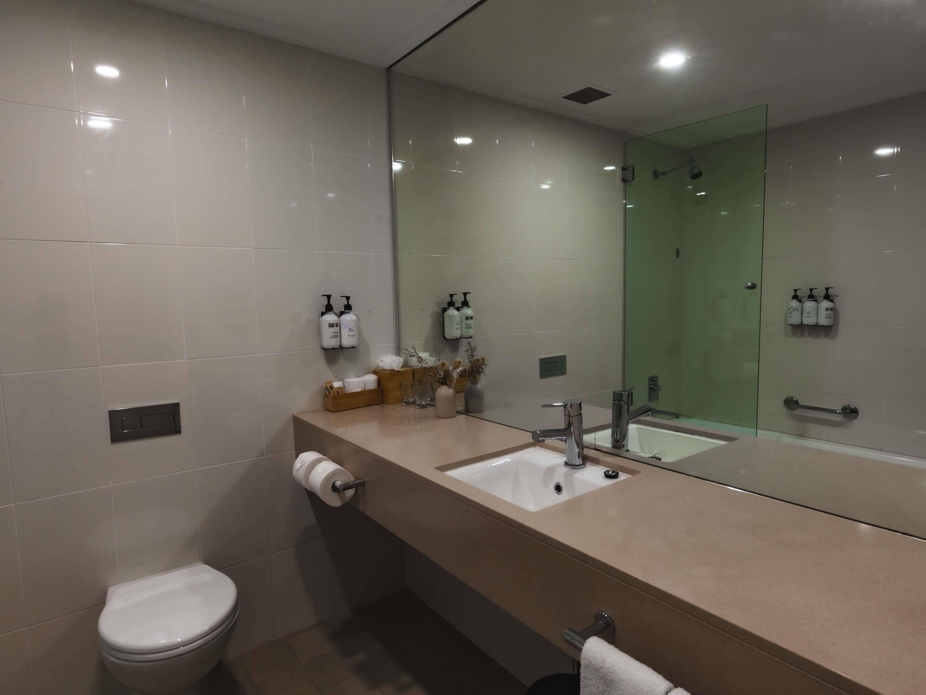 Un baño moderno con un espejo grande, dos lavamanos y un inodoro.