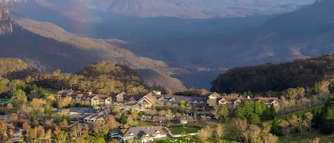A residential area with houses, a golf course, and a mountainous backdrop.