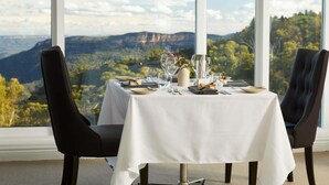 A dining table set for two with a mountain view through large windows.