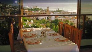 A table set for dining with a view of a coastal cityscape. - Hotel Suites La Siesta (Puerto Vallarta)