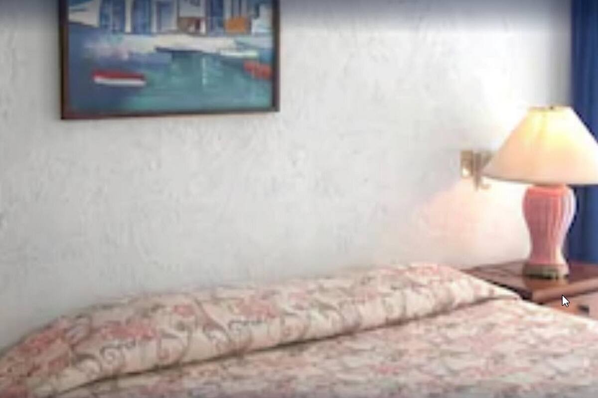 Een hotelkamer met een bed, twee bedlampen en een schilderij aan de muur.