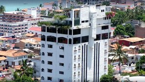 A multi-story building with balconies, surrounded by other residential buildings and palm trees. - Hotel Suites La Siesta (Puerto Vallarta)