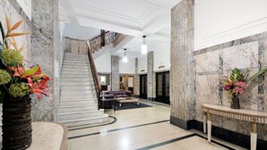 A lobby with a marble staircase, a reception desk, and a seating area. - Rothbury Hotel (Brisbane)