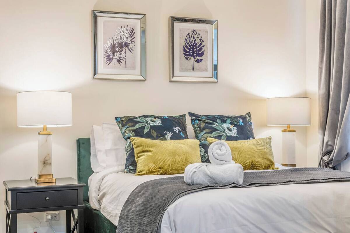 A hotel room with a bed, two nightstands, two lamps, and two framed floral artworks on the wall.