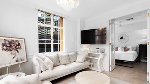 A modern, well-lit living room with a large window, a sofa, a coffee table, and a flat-screen TV. - Rothbury Hotel (Brisbane)