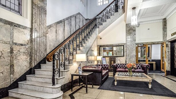 A grand lobby with marble staircases, leather sofas, and a chandelier. - Rothbury Hotel (Brisbane)