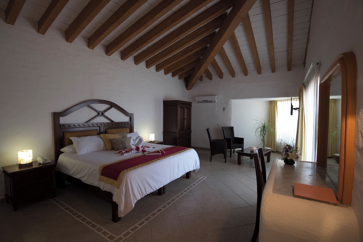 Un dormitorio con cama, mesitas de noche, armario, escritorio y silla.