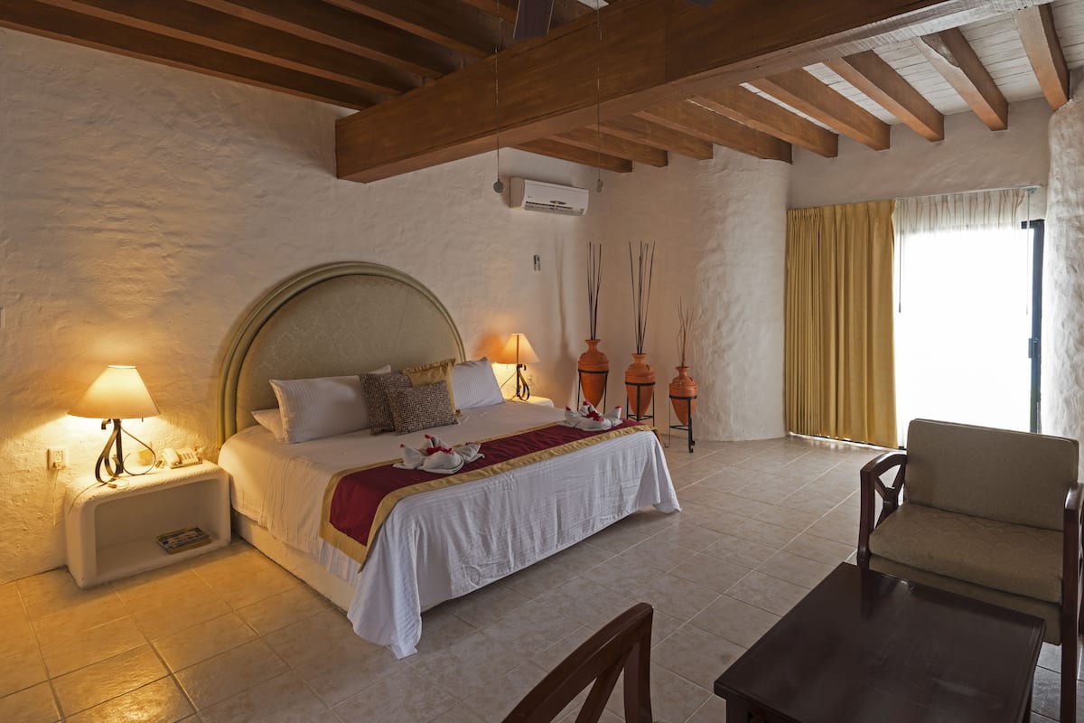 Ein Schlafzimmer mit einem großen Bett, Nachttischlampen, einem Sessel und einem kleinen Tisch.