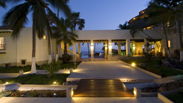 A resort with a covered walkway leading to a pool, palm trees, and a view of the ocean. - Hotel Punta Serena & Resorts- Couples Only (Tenacatita)