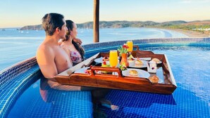 A couple in a hot tub with a tray of breakfast items and a view of the beach. - Hotel Punta Serena & Resorts- Couples Only (Tenacatita)