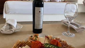 Habitación de hotel con una bandeja de desayuno ordenada, una botella de vino y una cama con cabecero de madera.